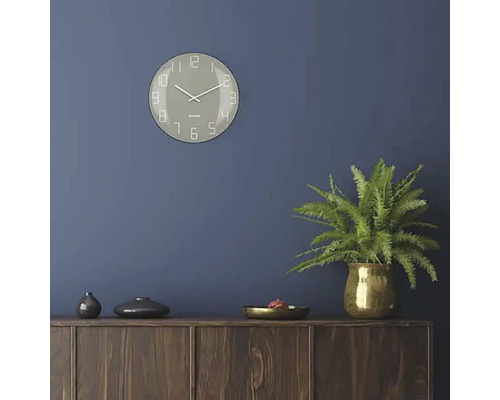 Cameră de zi cu ceas de perete, plantă de interior și comodă din lemn