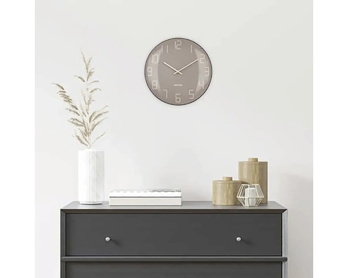 Scenă decorativă cu un ceas rotund de perete deasupra unei comode.