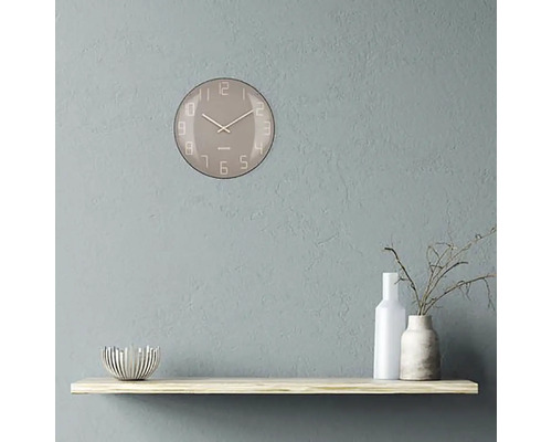 Ceas de perete cu cadran pe un raft cu obiecte decorative