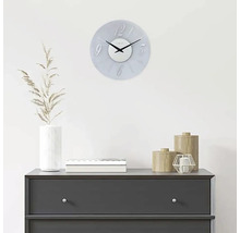 Ceas decorativ de perete deasupra unei comode cu accesorii pentru casă