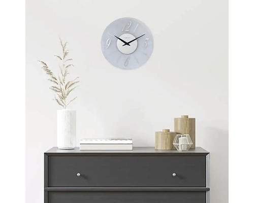 Ceas decorativ de perete deasupra unei comode cu accesorii pentru casă