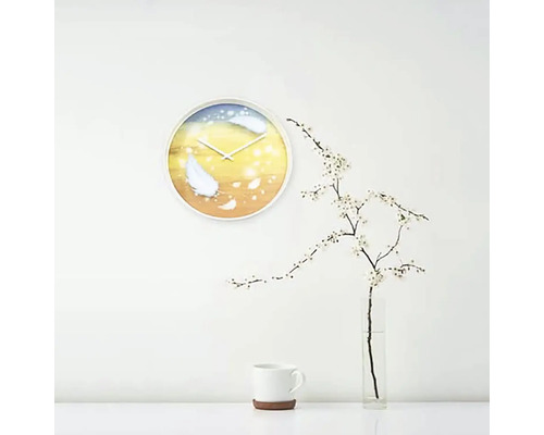 Ceas de perete cu motiv cu pene într-o cameră luminoasă