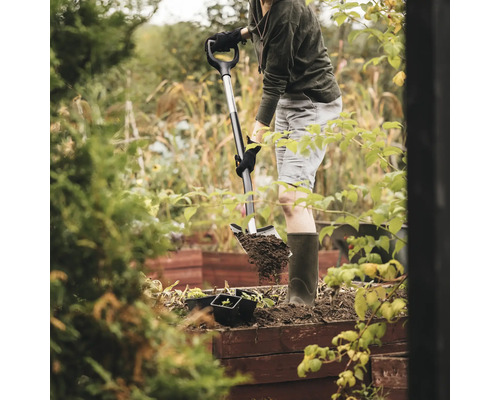 O persoană sapă cu o lopată într-un strat de grădină.