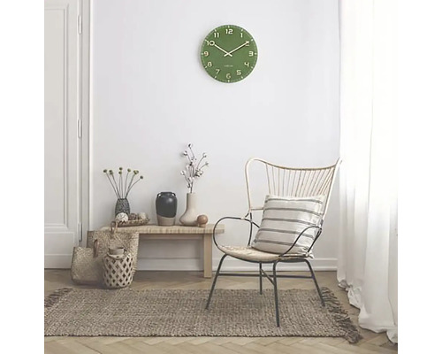 Scenă de living cu ceas de perete verde, fotoliu și covor