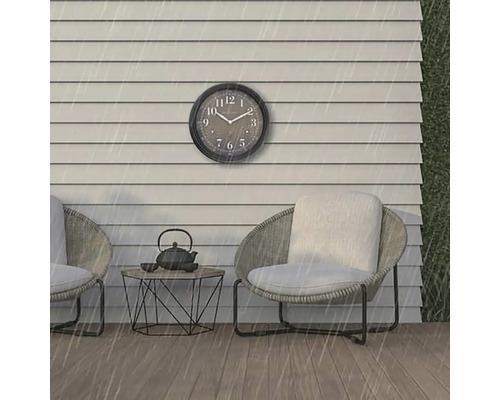 Scenă cu un ceas de perete, două scaune și o masă afară în ploaie.