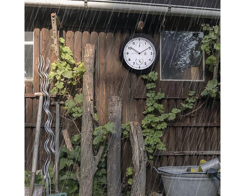 Scenă de grădină cu un ceas de exterior rezistent la intemperii pe un perete de lemn în ploaie.