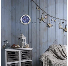 Spațiu de locuit decorativ cu ceas de perete, comodă, felinar, canapea și elemente decorative marine, cum ar fi stele de mare și scoici.