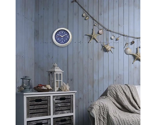 Spațiu de locuit decorativ cu ceas de perete, comodă, felinar, canapea și elemente decorative marine, cum ar fi stele de mare și scoici.