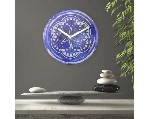 Ceas decorativ de perete cu model mandala deasupra unei grămezi de pietre
