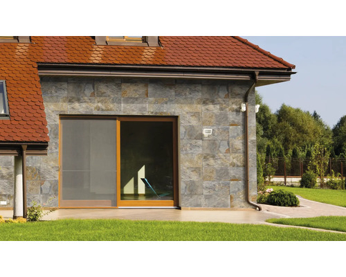 Fațadă de casă cu placare din piatră naturală, ușă glisantă și acoperiș roșu