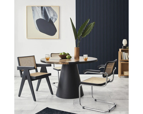 Sufragerie cu masă rotundă din lemn, cadre negre de scaun și opera de artă pe perete.