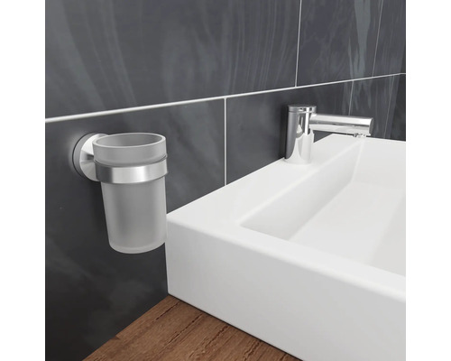 Suport de perete pentru pahar de periuțe de dinți din sticlă și metal lângă o chiuvetă