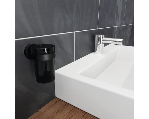 Pahar negru pentru periuțe de dinți, montat pe perete lângă o chiuvetă