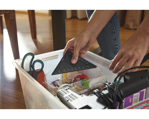 O persoană pune un raportor într-o cutie de depozitare cu scule.