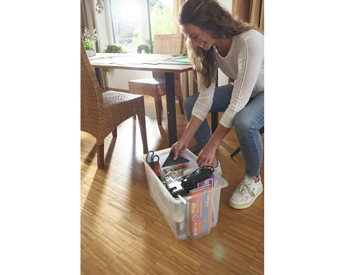 Femeie depozitând unelte și materiale într-o cutie de depozitare transparentă.