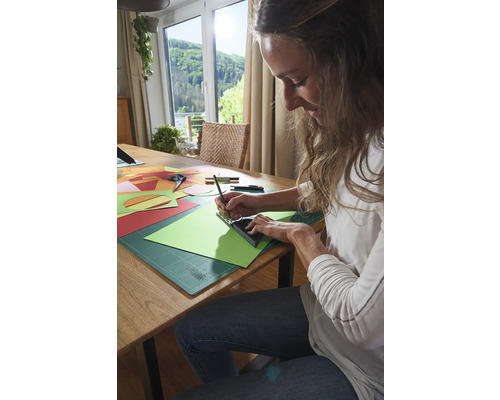 Femeie lucrând cu hârtie, riglă și creion la o masă.