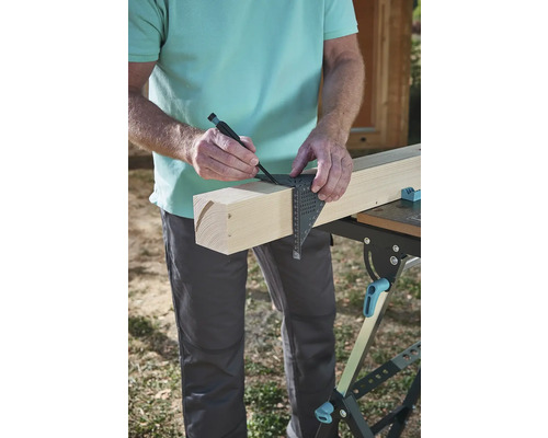 Meșterul marchează o scândură de lemn cu un echer și un creion.