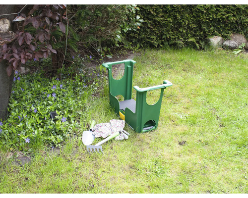 Scenă de grădină cu taburet de grădină, lopată, greblă și mănuși de grădină pe un gazon