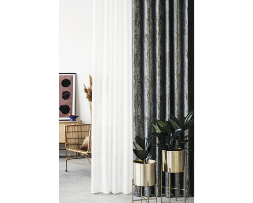 Amenajare decorativă a camerei cu perdele, fotoliu din ratan și plante de interior în ghivece aurii