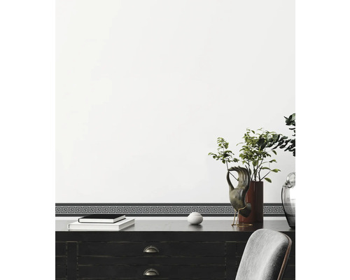 Bordură decorativă cu motiv meandru grecesc pe un perete deasupra unui birou.