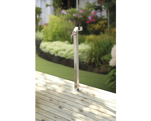 Robinet de grădină din metal pe terasă de lemn cu grădină în fundal