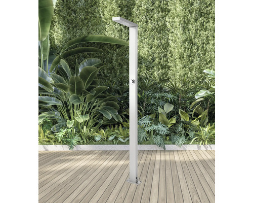 Duș de grădină din metal pe terasă de lemn în fața plantelor verzi