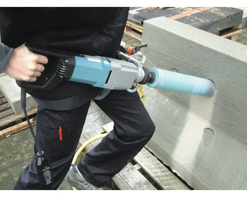 O persoană găurește un bloc de beton cu o mașină de carotat.