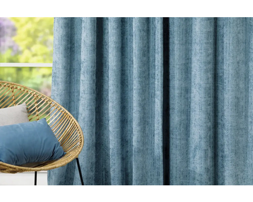 Cortină decorativă albastru deschis lângă un scaun de răchită în fața unei ferestre