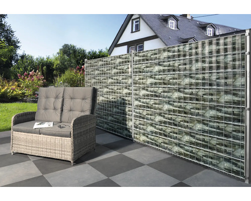 Scenă cu un perete gabion, o canapea din ratan și podea cu gresie în grădină