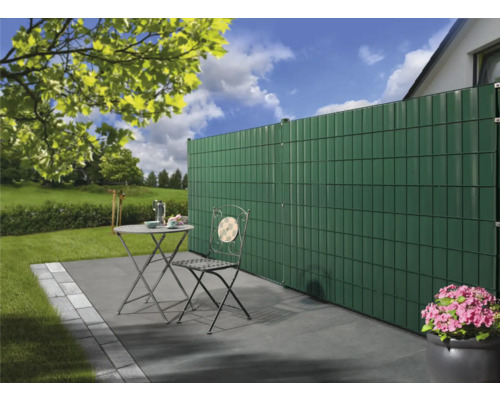 Scenă de grădină cu paravan de confidențialitate, masă de grădină și scaun pe o terasă