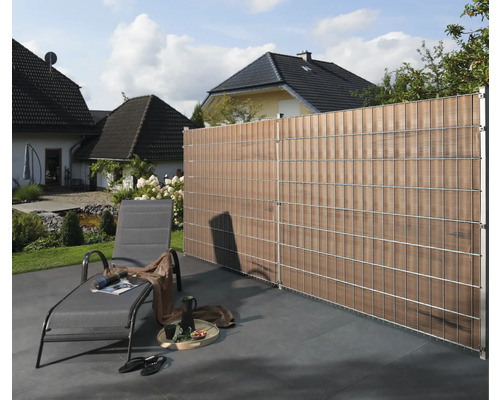 Scenă de grădină cu gard de intimitate, șezlong și casă în fundal