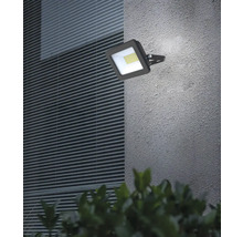 Reflector LED exterior pătrat montat pe un perete de casă.