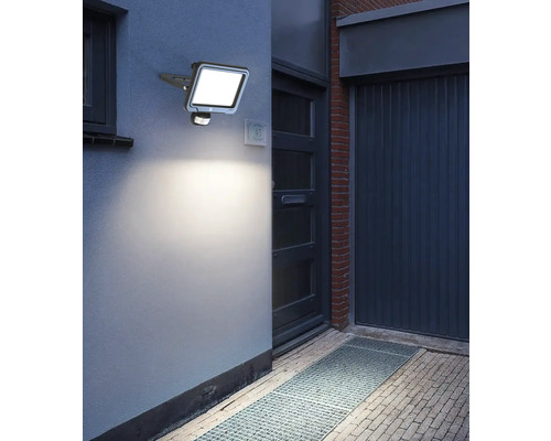 Fotografie de exterior a unui corp de iluminat exterior cu LED iluminat cu senzor de mișcare pe un perete de casă