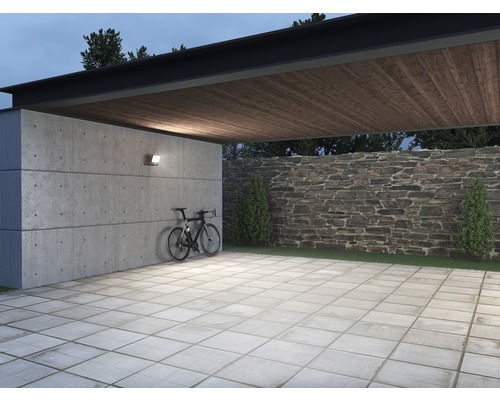 Spațiu exterior cu perete de beton, perete de piatră, plăci de pavaj, bicicletă și iluminat exterior