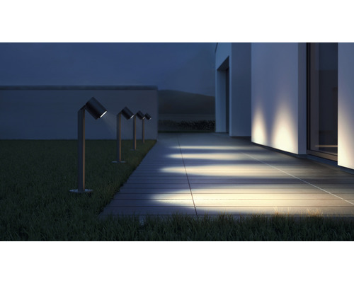 Alee iluminată cu mai multe lămpi de grădină lângă o casă