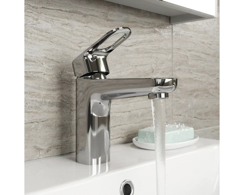 Baterie de lavoar lucioasă din metal pe o chiuvetă cu apă curgătoare