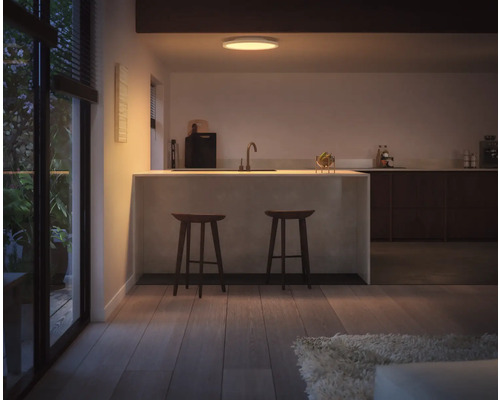 Fotografie de interior a unei bucătării cu o insulă de gătit și două scaune de bar.