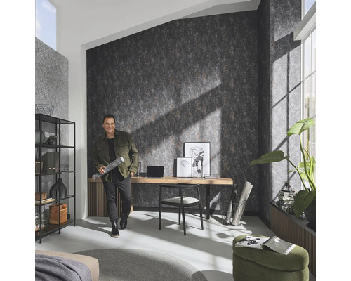 Cameră de zi cu tapet cu model, birou și bărbat cu rolă de tapet