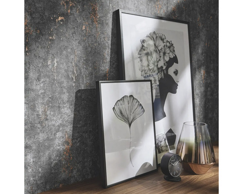 Scenă decorativă cu două imagini înrămate, un ceas și o vază pe un raft în fața unui perete texturat.