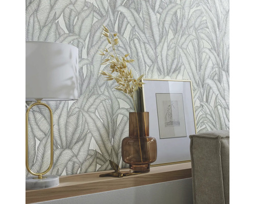 Tapetă decorativă cu model de frunze într-un living cu lampă și decorațiuni