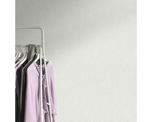 Tapetă de perete deschisă la culoare cu model textil lângă un suport pentru haine