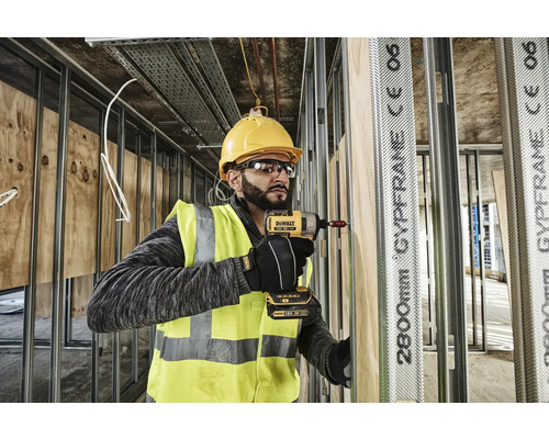 Artizan cu o șurubelniță cu impact cu acumulator care efectuează lucrări de gips-carton cu montanți metalici și plăci de lemn