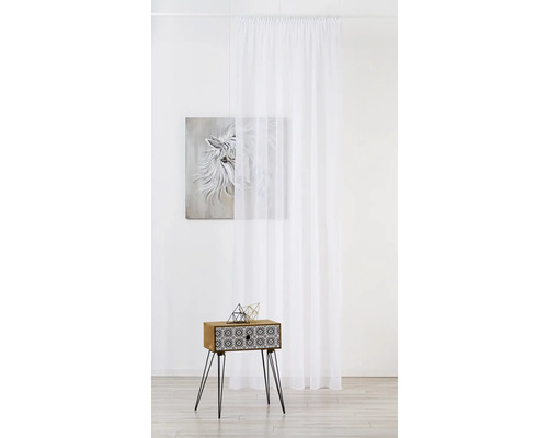 Scenă cu o perdea albă din voal, un tablou și o noptieră cu decorațiuni geometrice.