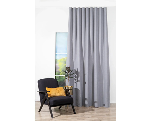 Vedere a camerei cu perdea gri, fotoliu și măsuță laterală