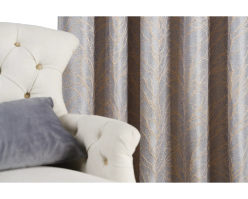 Perdea decorativă cu model de frunze lângă un fotoliu.