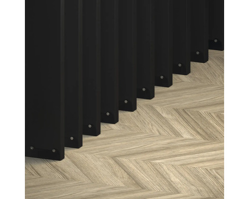 Prim-plan cu elemente de gard negre pe o pardoseală de parchet deschisă la culoare, cu model herringbone