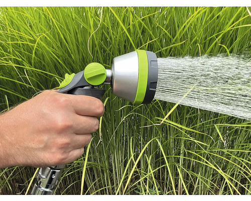 O mână ține un pulverizator de grădină care stropește cu apă.