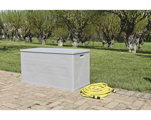 Ladă de grădină gri cu furtun de grădină galben în grădină