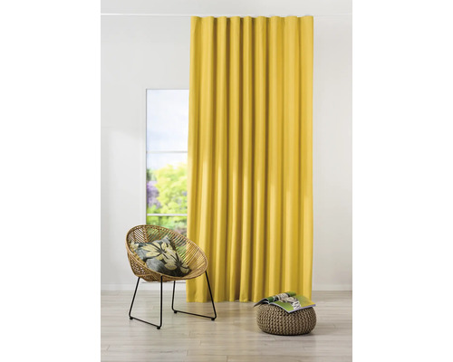 Cortină galbenă lângă o fereastră, un scaun din ratan și un taburet