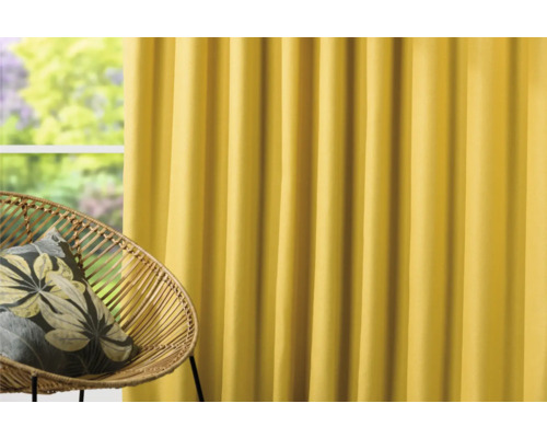 Perdea galbenă lângă un scaun de ratan cu pernă.